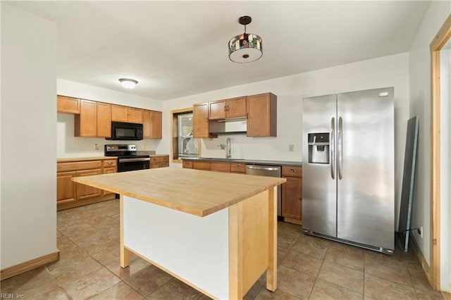 kitchen with baseboards, a sink, a kitchen island, and appliances with stainless steel finishes