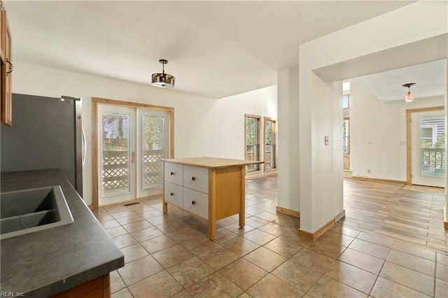 kitchen with baseboards, light tile patterned floors, a sink, and freestanding refrigerator