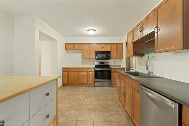 kitchen with a sink, brown cabinets, appliances with stainless steel finishes, and light tile patterned floors