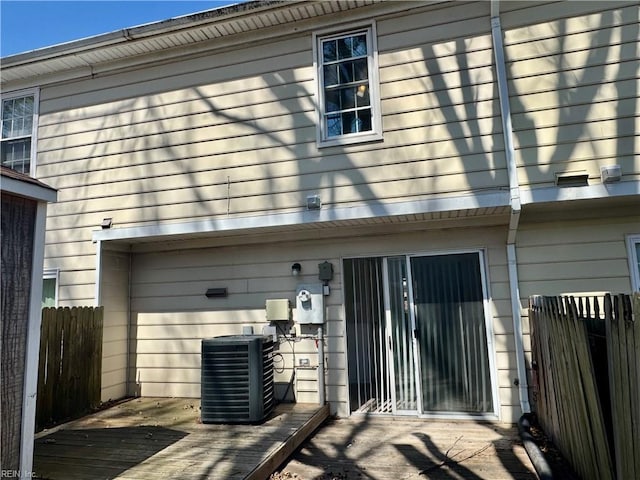 back of property with fence and central AC
