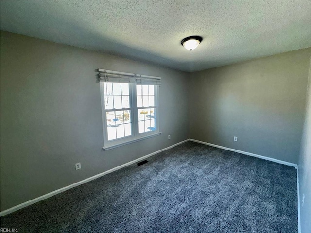 unfurnished room with baseboards, dark colored carpet, a textured ceiling, and visible vents
