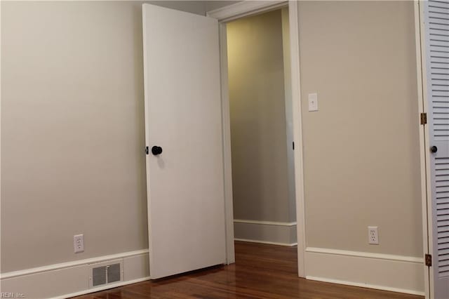 empty room with wood finished floors, baseboards, and visible vents