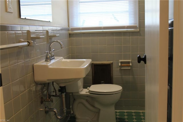 bathroom with a sink, tile walls, toilet, and tile patterned floors