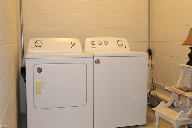 laundry area with concrete block wall, separate washer and dryer, and laundry area