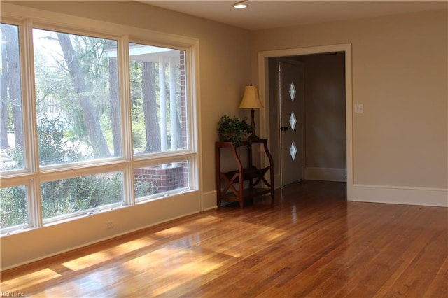 empty room with baseboards, wood finished floors, and recessed lighting