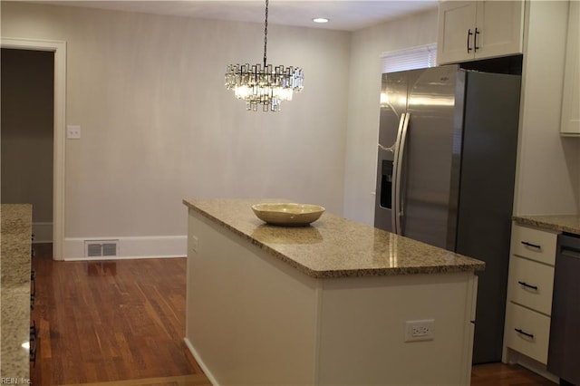 kitchen featuring stainless steel fridge, a center island, visible vents, white cabinets, and light stone countertops