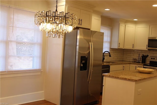 kitchen with white cabinetry, stainless steel appliances, backsplash, a sink, and a notable chandelier