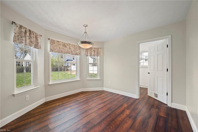 unfurnished dining area with dark wood-style floors, a wealth of natural light, and baseboards
