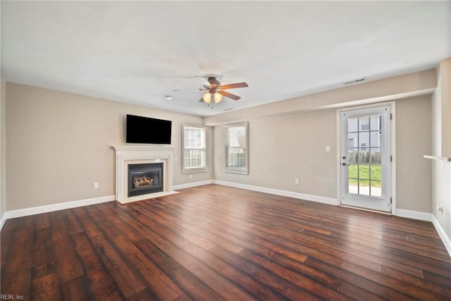 unfurnished living room featuring a fireplace with flush hearth, baseboards, ceiling fan, and dark wood-style flooring