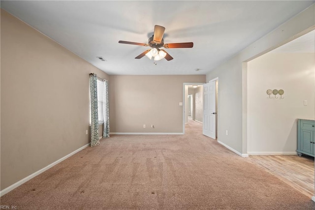 spare room featuring baseboards, visible vents, a ceiling fan, and light colored carpet