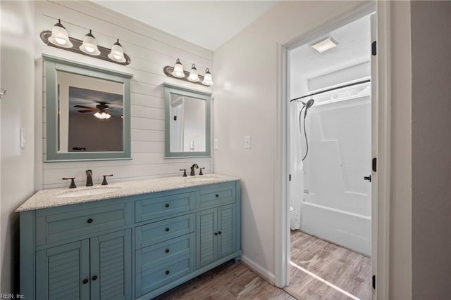 bathroom featuring double vanity, a sink, shower / tub combination, and wood finished floors
