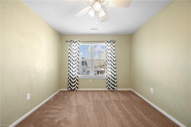 carpeted spare room featuring baseboards, ceiling fan, and visible vents