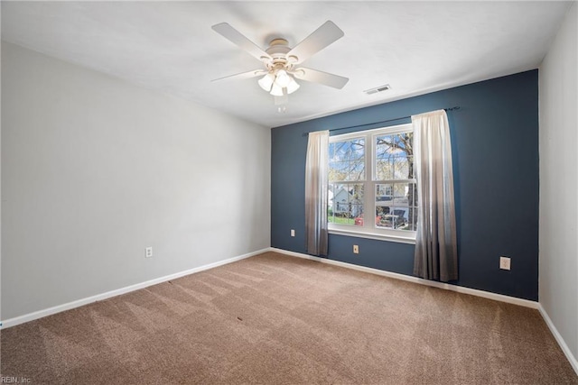 carpeted empty room with baseboards, ceiling fan, and visible vents