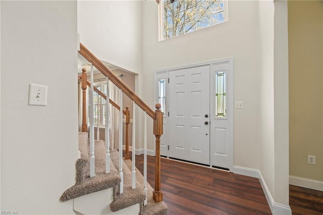 entrance foyer with stairs, a high ceiling, wood finished floors, and baseboards