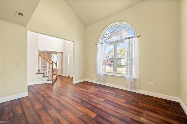 unfurnished room with dark wood-type flooring, stairs, baseboards, and a healthy amount of sunlight
