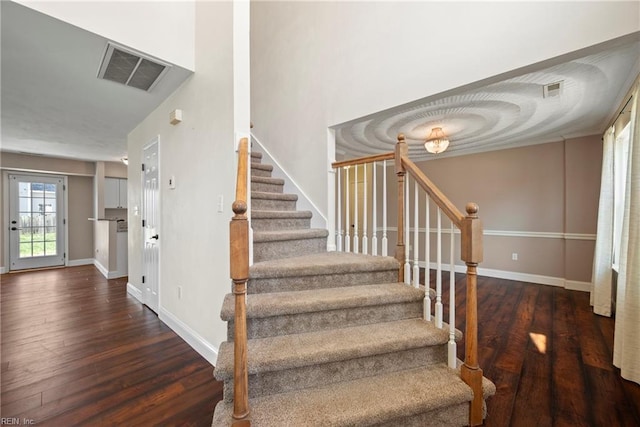 staircase featuring visible vents, baseboards, and wood finished floors