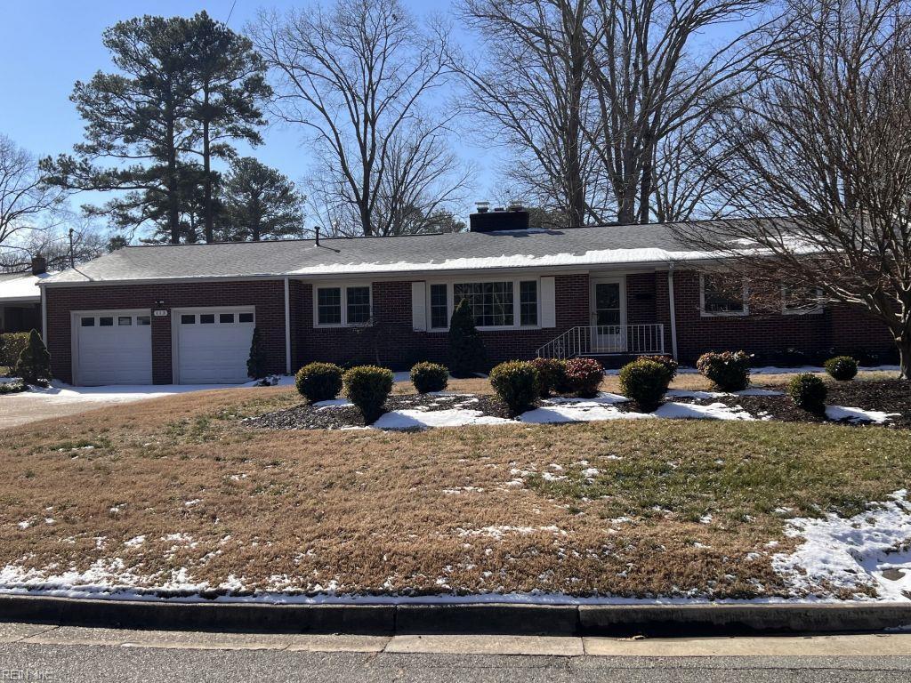 single story home with a chimney, an attached garage, and brick siding