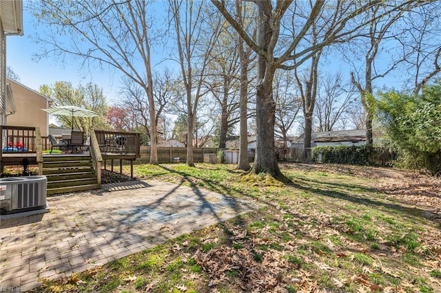 view of yard with a patio area, central AC, a wooden deck, and a fenced backyard