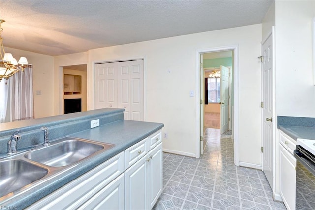 kitchen featuring a chandelier, a textured ceiling, a sink, and electric range