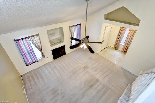carpeted living area featuring a textured ceiling, ceiling fan, a fireplace, and lofted ceiling