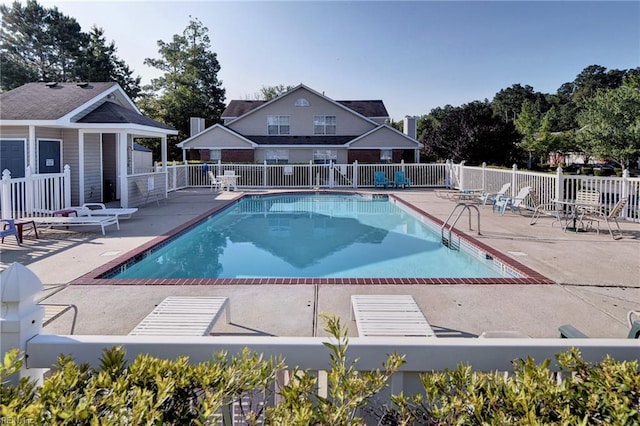 community pool with a patio area and fence