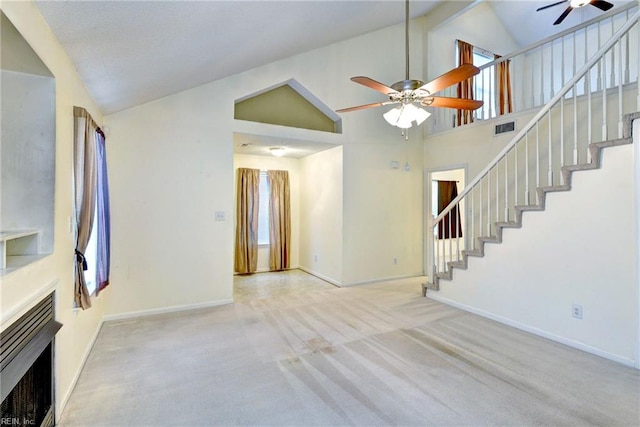 unfurnished living room featuring baseboards, a fireplace, stairway, a ceiling fan, and carpet floors