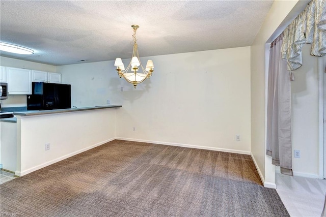 interior space featuring black refrigerator, a textured ceiling, carpet flooring, stainless steel microwave, and a notable chandelier