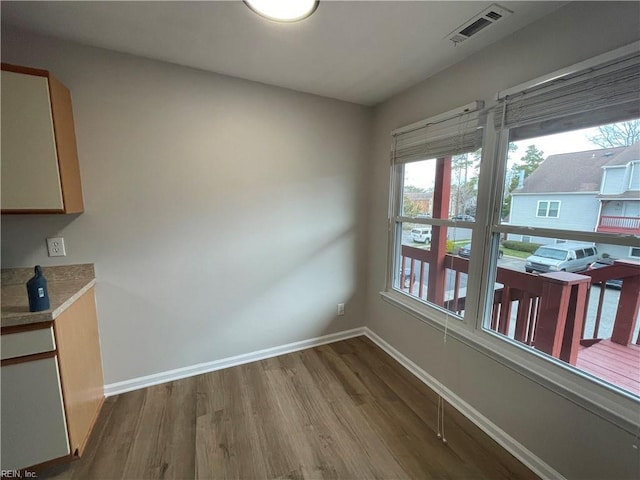 unfurnished dining area with wood finished floors, baseboards, and visible vents