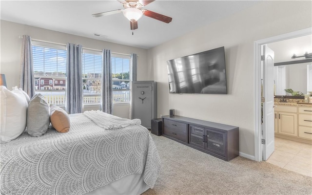 bedroom featuring a sink, ensuite bathroom, baseboards, light colored carpet, and ceiling fan
