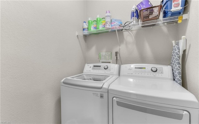 laundry room featuring washing machine and clothes dryer, laundry area, and a textured wall