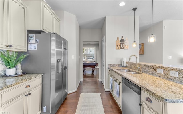 kitchen with stainless steel appliances, dark wood-type flooring, a sink, light stone counters, and a peninsula