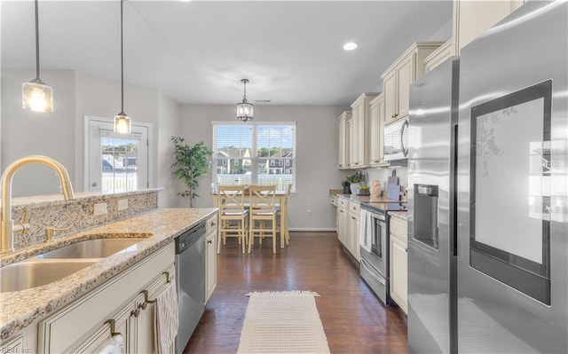 kitchen with decorative light fixtures, stainless steel appliances, dark wood finished floors, a sink, and light stone countertops