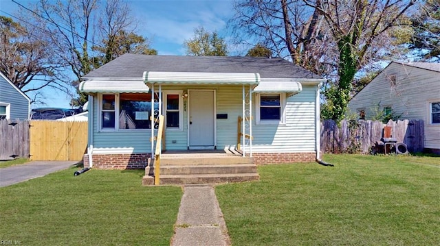 bungalow-style home with a front yard, fence, and covered porch