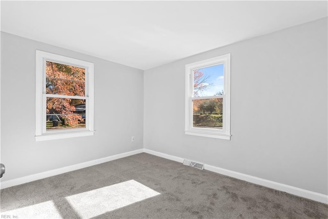 carpeted empty room featuring baseboards and visible vents