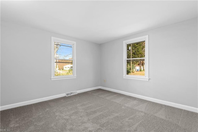 carpeted spare room with baseboards, a healthy amount of sunlight, and visible vents