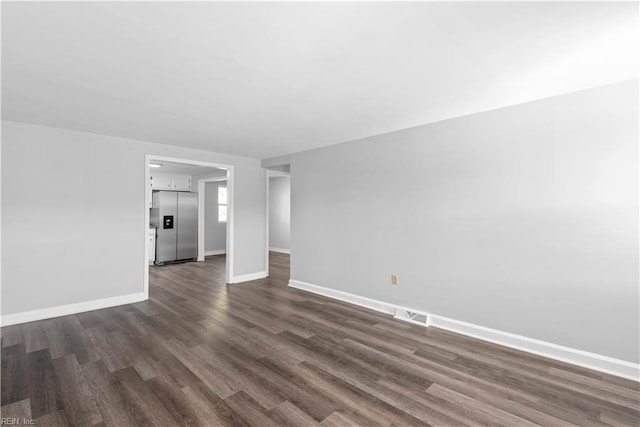 unfurnished living room with baseboards, visible vents, and dark wood-style flooring