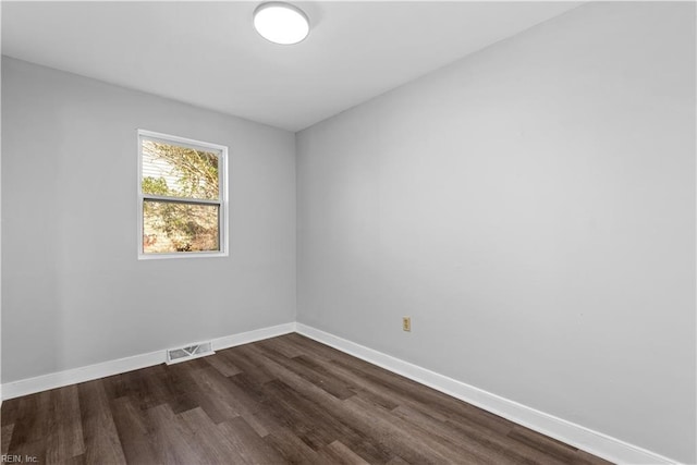 spare room featuring dark wood-type flooring, baseboards, and visible vents