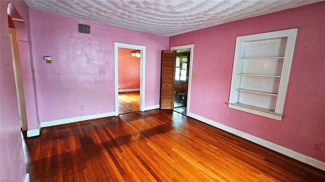 380 Hobson Ave, Hampton, VA 23661 - empty room featuring baseboards, a textured ceiling, built in shelves, hardwood / wood-style flooring, and visible vents