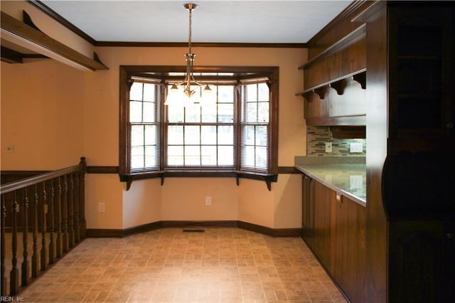 kitchen featuring tasteful backsplash, crown molding, baseboards, a chandelier, and pendant lighting