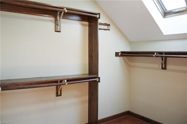 walk in closet with dark wood-style floors and vaulted ceiling with skylight