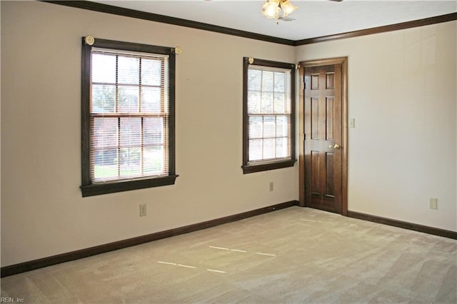 unfurnished room with light colored carpet, a wealth of natural light, crown molding, and baseboards