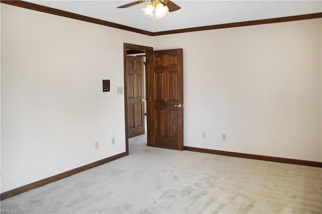 empty room featuring light colored carpet, crown molding, baseboards, and a ceiling fan