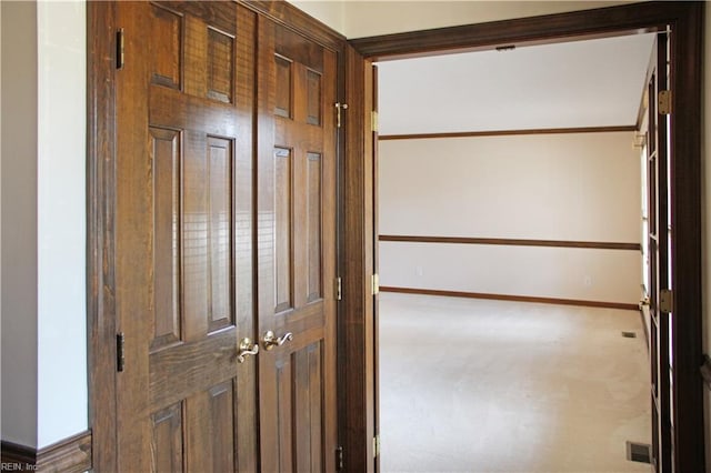 hall with baseboards, visible vents, and carpet