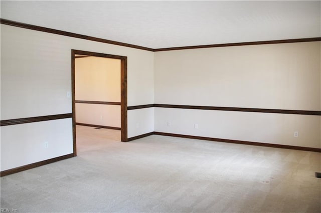 spare room with crown molding, baseboards, and light colored carpet