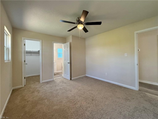 unfurnished bedroom with a spacious closet, carpet flooring, and baseboards