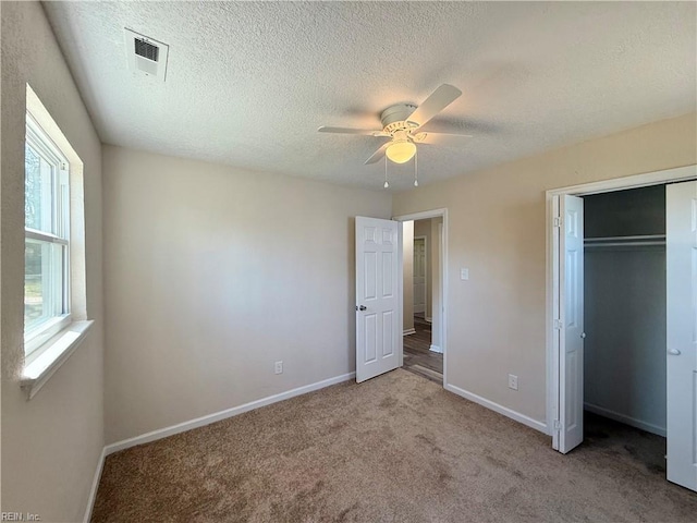 unfurnished bedroom with a closet, carpet flooring, a textured ceiling, baseboards, and ceiling fan