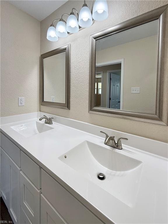 full bath with double vanity, a sink, and a textured wall