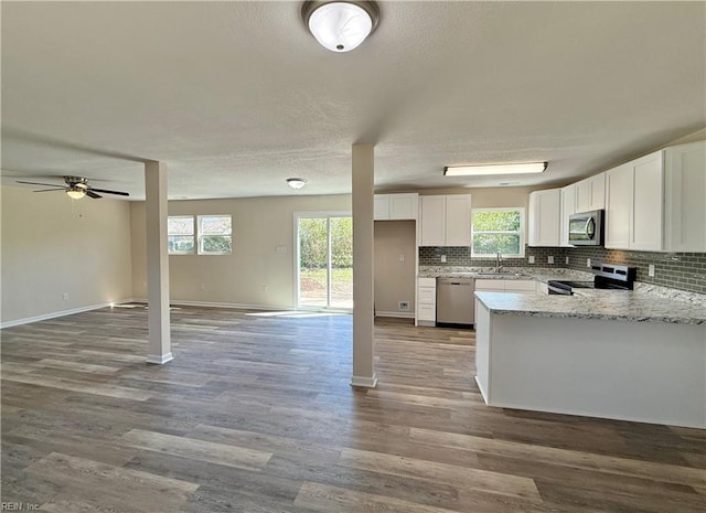 kitchen with decorative backsplash, a sink, stainless steel appliances, and open floor plan