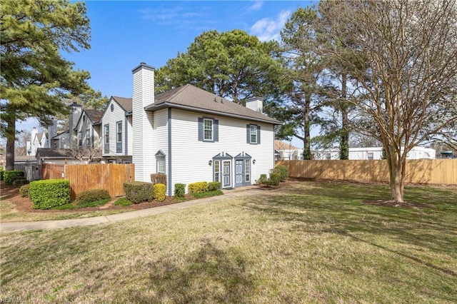 exterior space with a lawn, a chimney, and fence