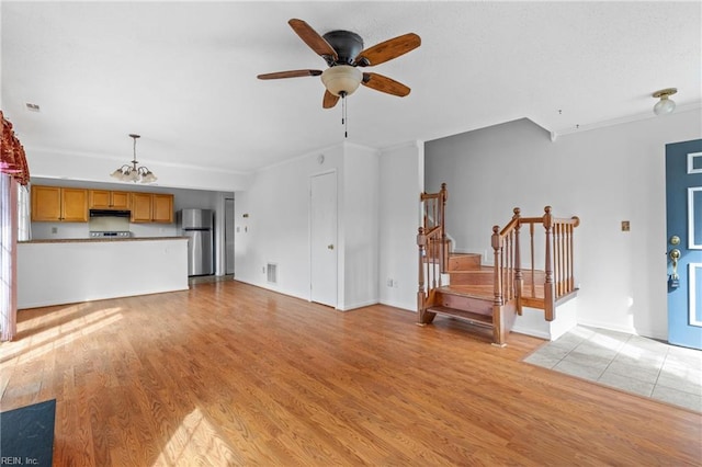 724 Oleander Cir, Virginia Beach, VA 23464 - unfurnished living room featuring crown molding, stairs, ceiling fan with notable chandelier, visible vents, and light wood-style flooring
